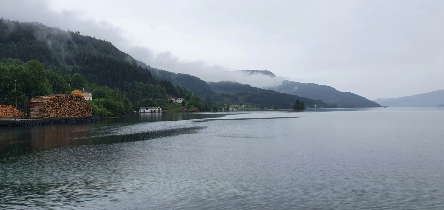 Norwegian fjord with traditional wooden houses and snow-capped mountains — the Scandinavian landscape that shaped its culture
